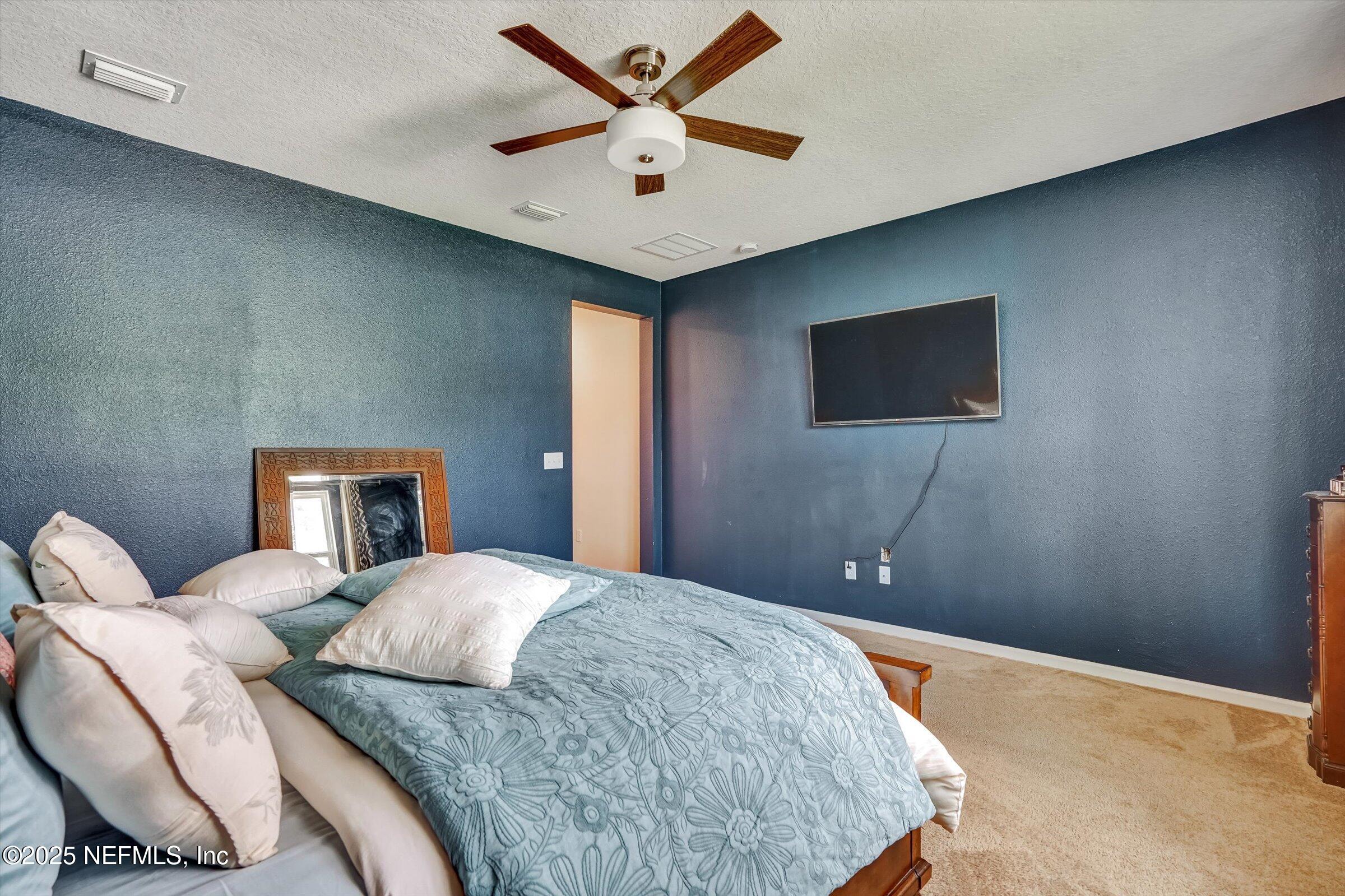 410 Downs Corner Road St. Augustine, FL 32092 - Photo 27 of 45 a bedroom with a bed and a chandelier