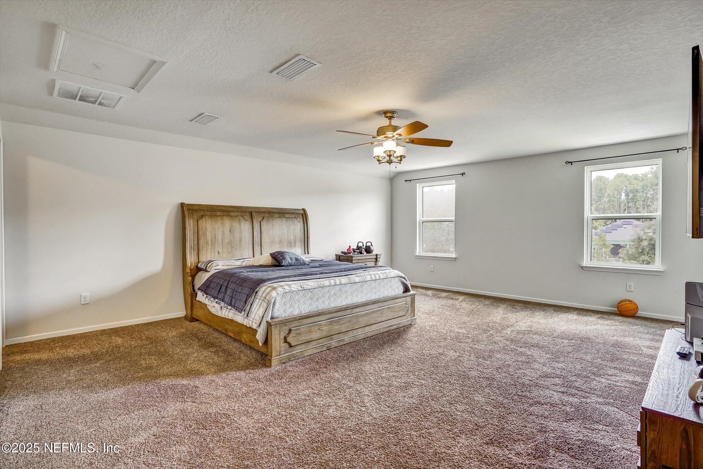 410 Downs Corner Road St. Augustine, FL 32092 - Photo 30 of 45 a spacious bedroom with a bed and a chandelier