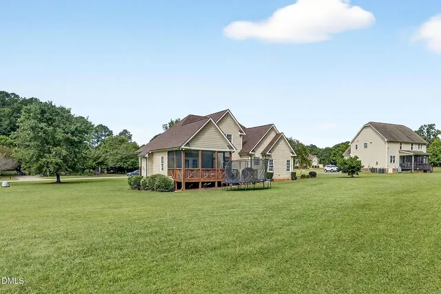 a view of a house with a big yard and large trees