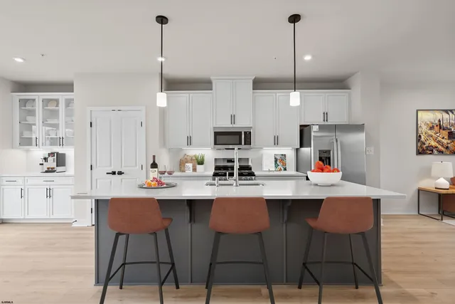 a kitchen with stainless steel appliances a dining table chairs and white cabinets