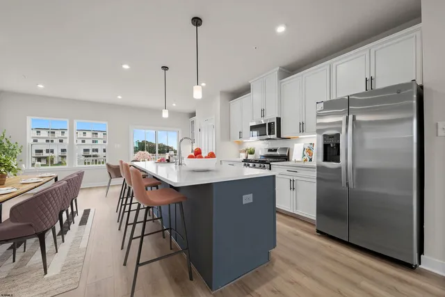 a kitchen with stainless steel appliances granite countertop a sink a stove a refrigerator and island with wooden floor