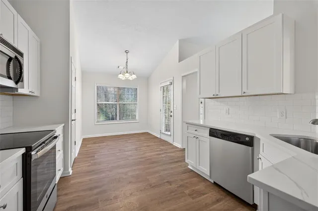 a kitchen with granite countertop white cabinets and black appliances