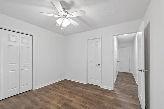 wooden floor in an empty room with a chandelier fan