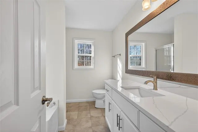 a bathroom with a granite countertop sink a toilet and a mirror