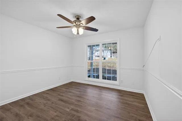 an empty room with wooden floor fan and windows