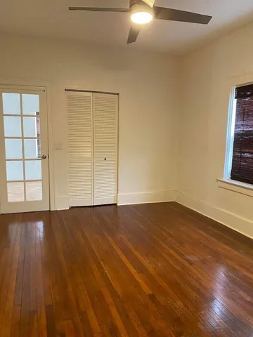 a view of an empty room with wooden floor and windows