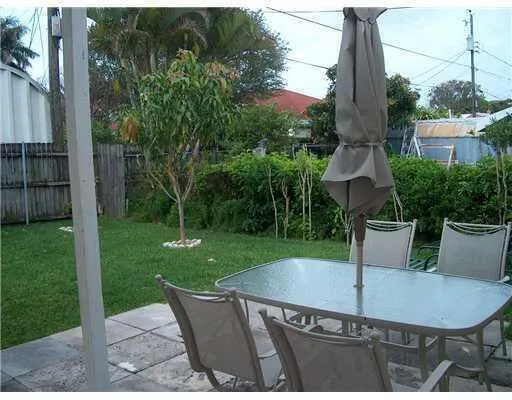 a view of a backyard with table and chairs potted plants and palm tree