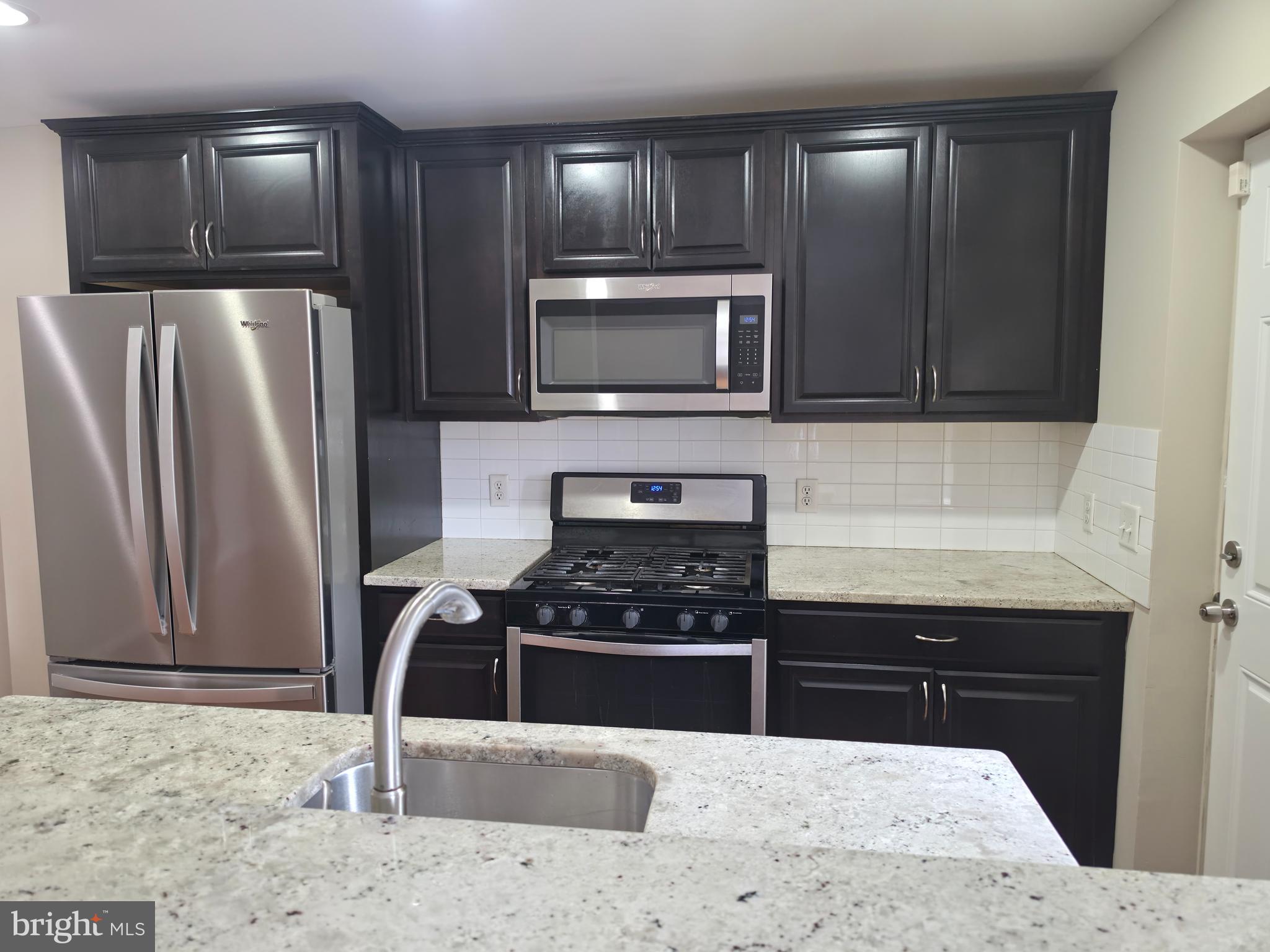 2028 Hillenwood Road Baltimore, MD 21239 - Photo 5 of 18 a kitchen with granite countertop a refrigerator and a stove top oven