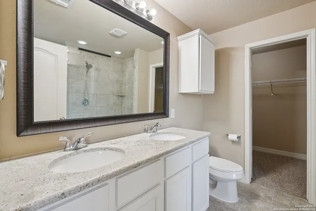 a bathroom with a granite countertop sink toilet mirror and shower