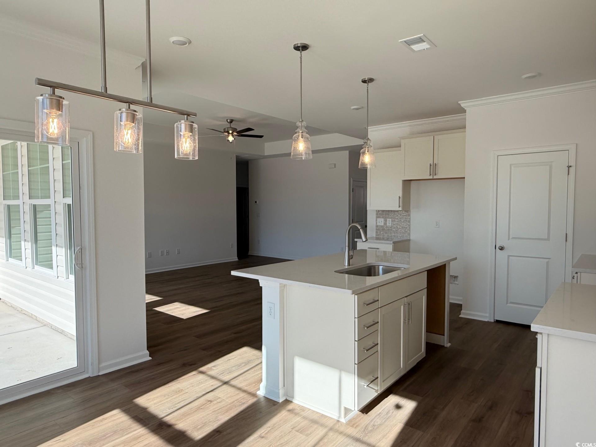 112 Cascade Drive Conway, SC 29527 - Photo 3 of 13 Kitchen featuring decorative light fixtures, ornamental molding, a ceiling fan, a center island with sink, and backsplash