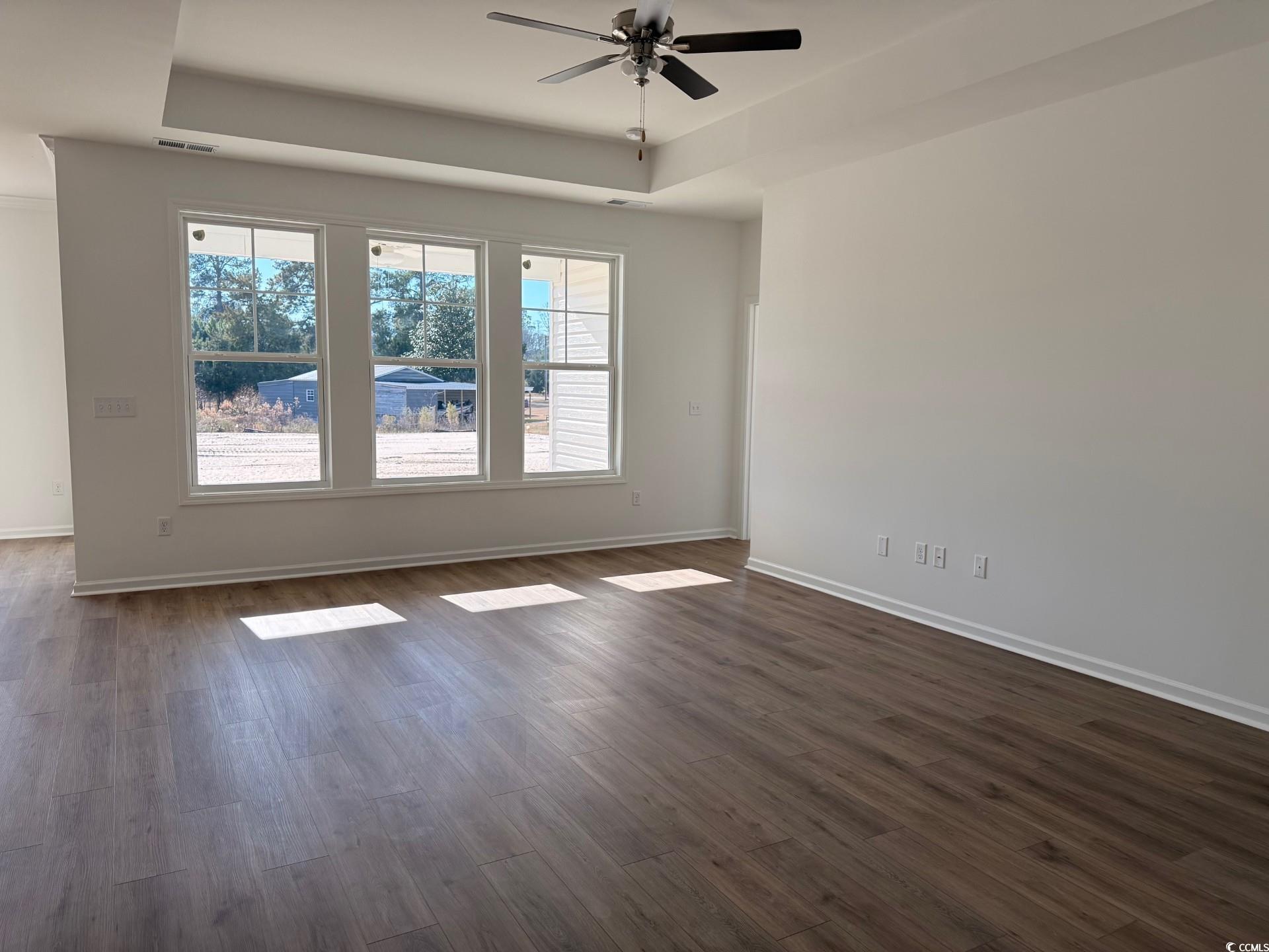 112 Cascade Drive Conway, SC 29527 - Photo 6 of 13 Empty room featuring dark wood finished floors, a tray ceiling, and ceiling fan