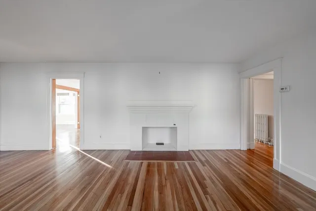 a view of empty room with wooden floor and fireplace