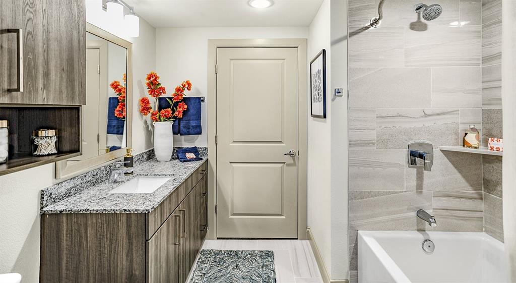 a bathroom with a granite countertop tub sink and mirror