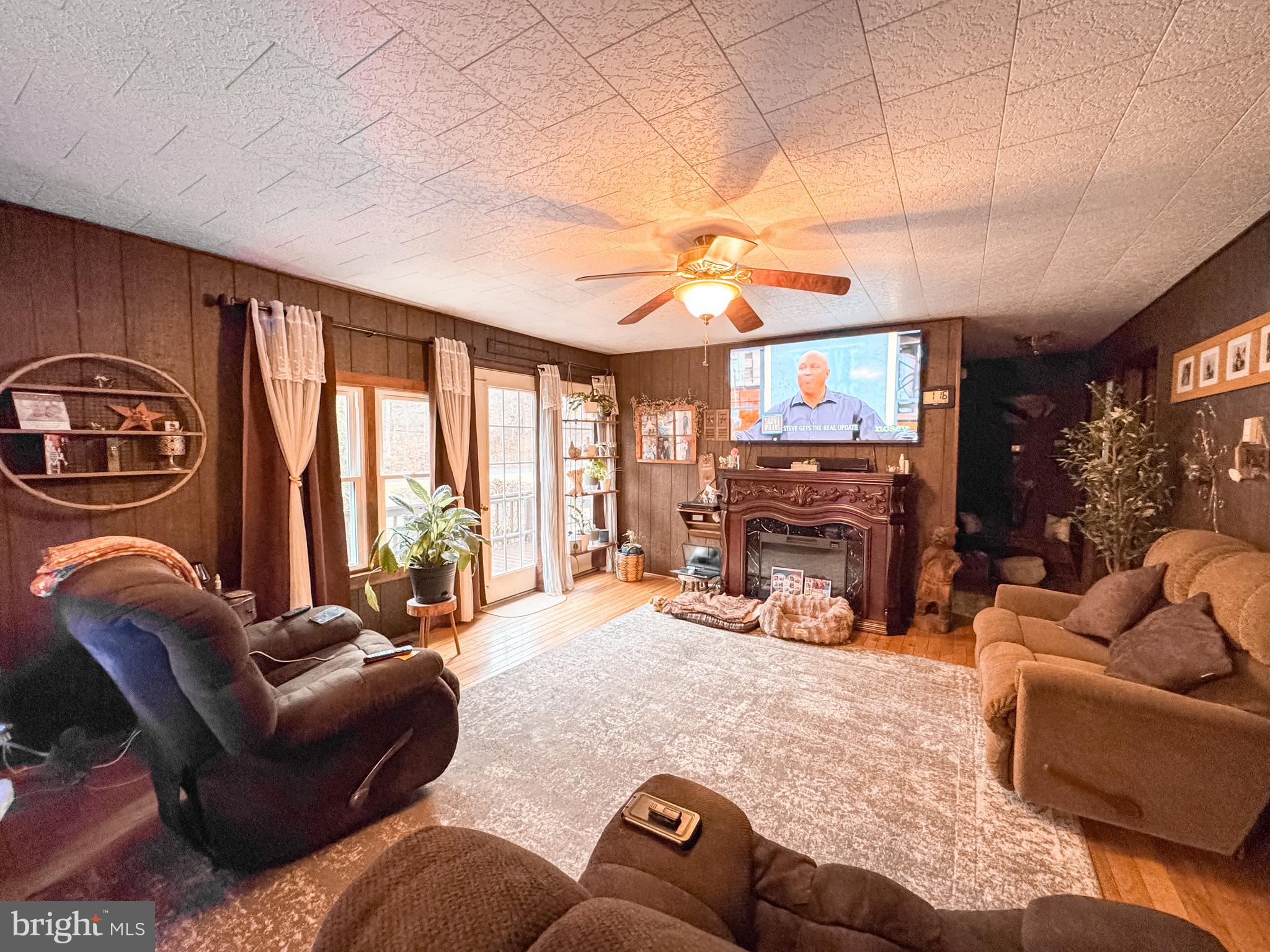 12522 Bakers Hollow Road Hesston, PA 16647 - Photo 13 of 72 a living room with furniture a fireplace a flat screen tv and a large window