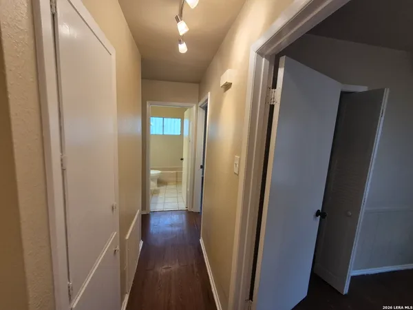 an empty room with wooden floor fan and windows