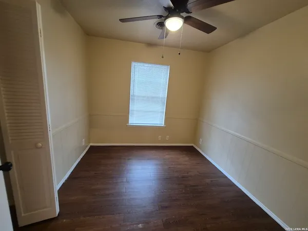 an empty room with wooden floor chandelier fan and closet area