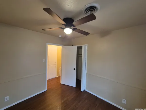 an empty room with wooden floor closet and windows