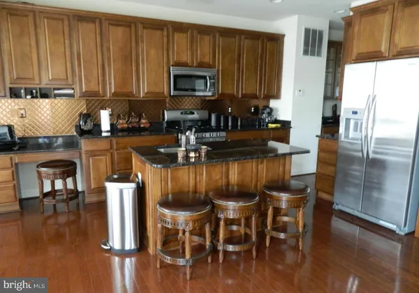 a kitchen with stainless steel appliances granite countertop a stove a refrigerator a kitchen island a table and chairs