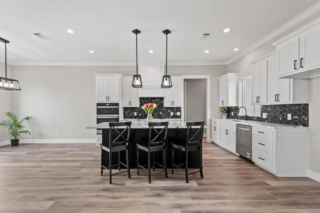 a large kitchen with kitchen island a dining table chairs and a wooden floor