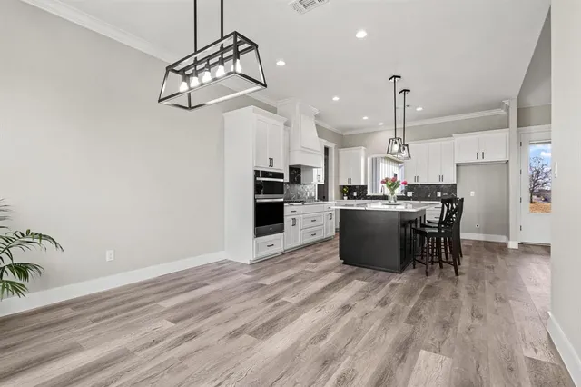 a view of an empty room with wooden floor and a ceiling fan