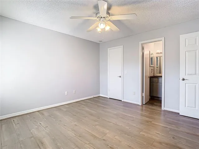 an empty room with a chandelier fan and windows