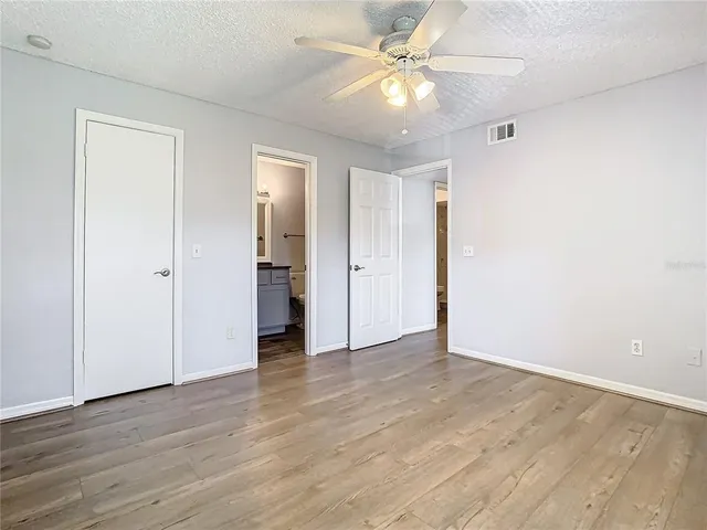 an empty room with wooden floor and ceiling fan