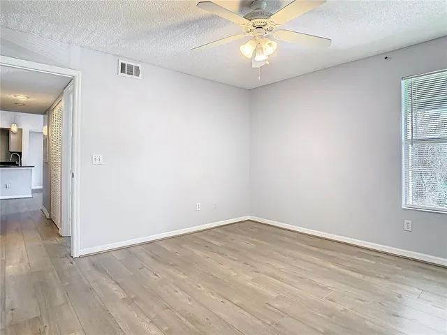 an empty room with wooden floor fan and windows