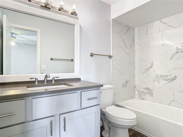 a bathroom with a granite countertop sink toilet mirror and bathtub