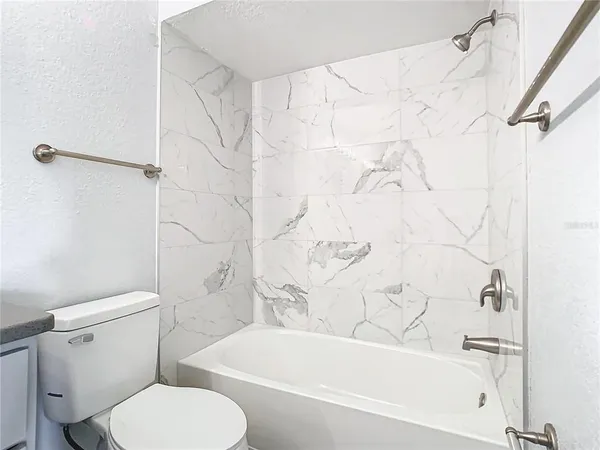 a white toilet sitting next to a bath tub and a shower