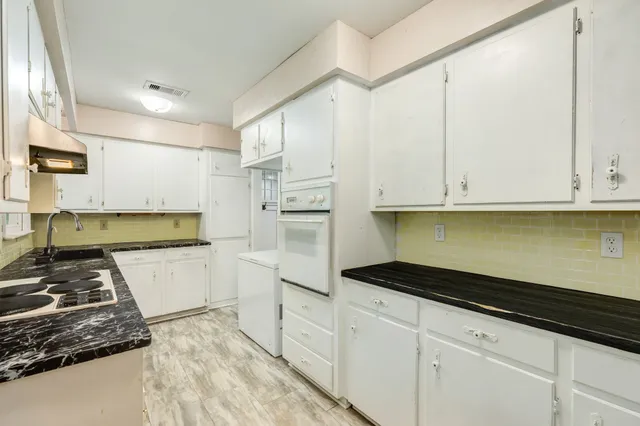 a kitchen with granite countertop white cabinets and stainless steel appliances