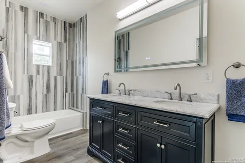 a bathroom with a granite countertop sink vanity mirror bathtub shower and a toilet