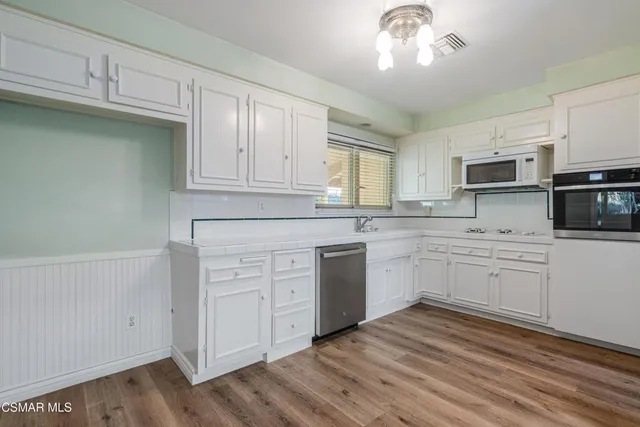 a kitchen with cabinets stainless steel appliances a sink and a window