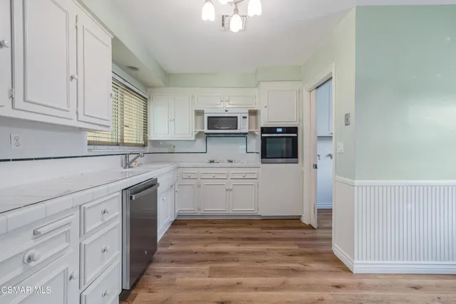 a kitchen with granite countertop white cabinets and stainless steel appliances