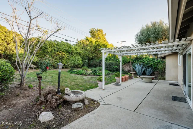 a view of a backyard with couches plants and large tree
