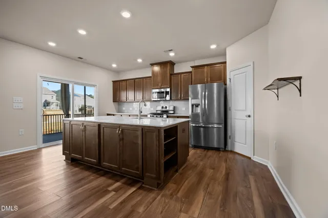 a kitchen with wooden floors stainless steel appliances and window