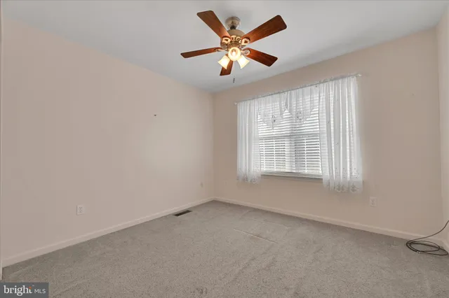 a view of an empty room and chandelier fan