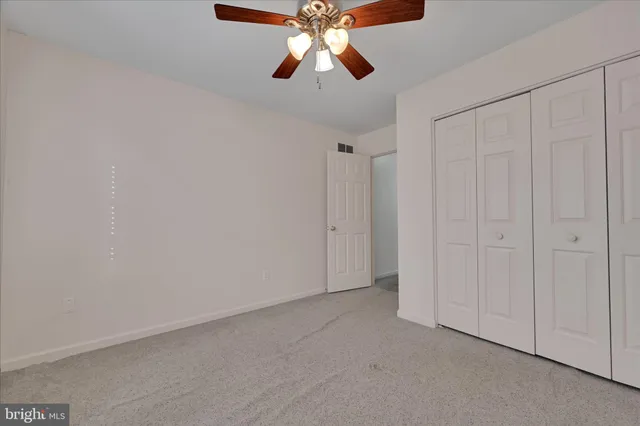 an empty room with ceiling fan and window