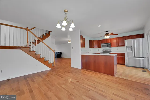 a kitchen with stainless steel appliances kitchen island wooden floors granite counter space and a sink
