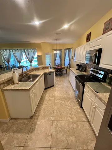 a living room with stainless steel appliances kitchen island granite countertop a sink a stove and a wooden floors