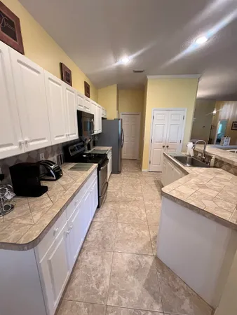 a kitchen with stainless steel appliances a stove a sink a microwave a sink a refrigerator and white cabinets
