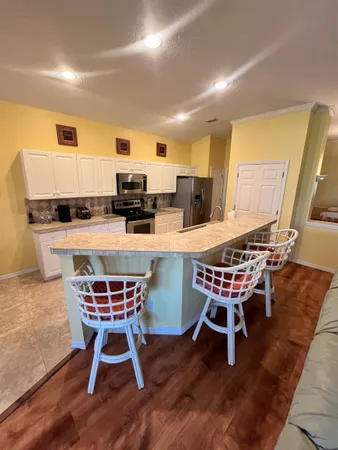 a dining room with stainless steel appliances kitchen island granite countertop a table chairs and a refrigerator