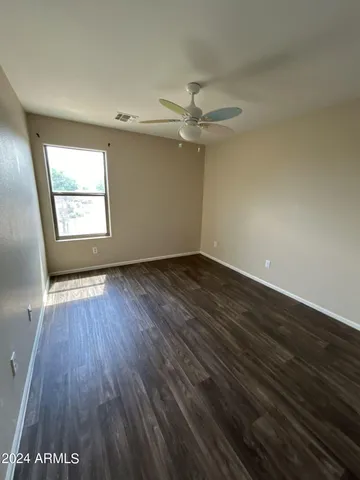 an empty room with wooden floor fan and windows