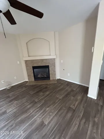 a view of an empty room with wooden floor fireplace and a window