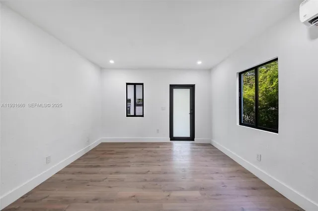 a view of an empty room with window and wooden floor