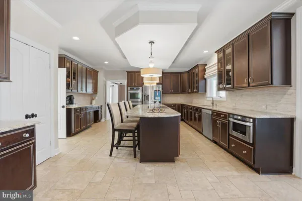 a kitchen with stainless steel appliances granite countertop table chairs stove and oven