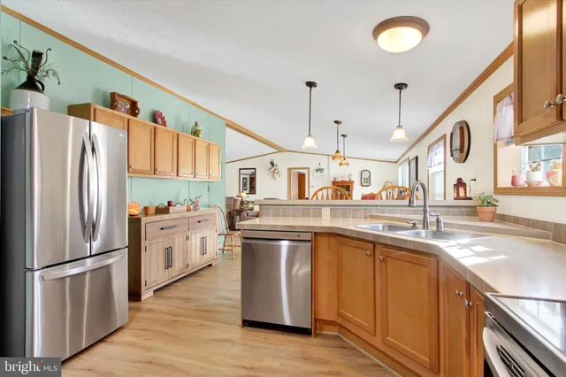 a kitchen with stainless steel appliances granite countertop a refrigerator a sink dishwasher a stove and a sink with wooden floor