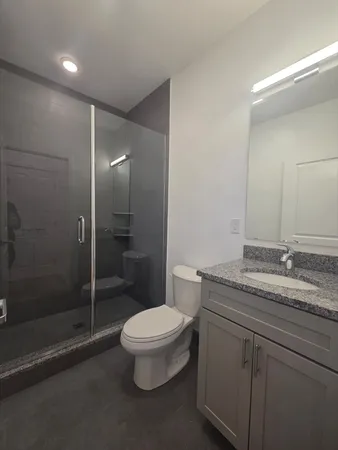 a bathroom with a granite countertop sink a toilet and shower