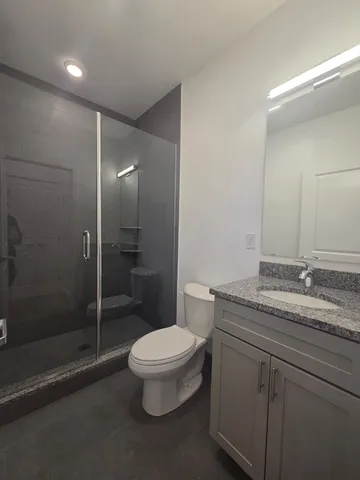 a bathroom with a granite countertop sink a toilet and shower