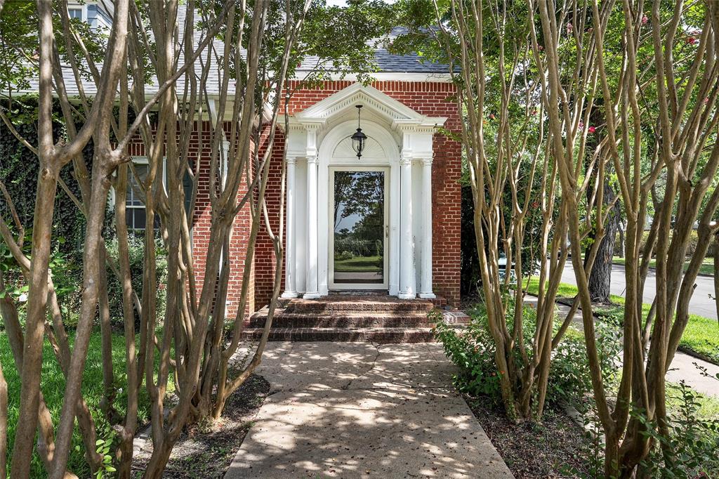 Property entrance featuring brick siding and a shingled roof