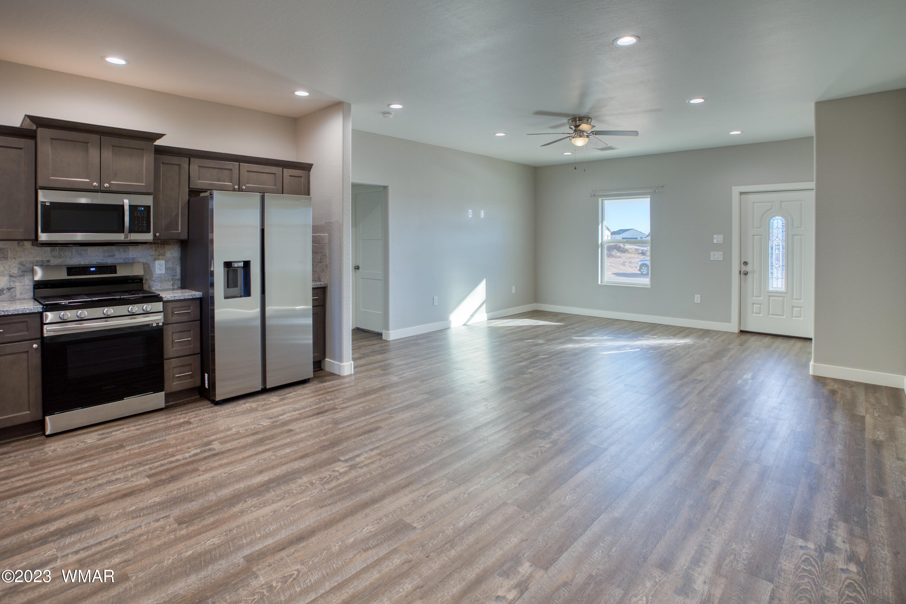 260 Granite Circle Taylor, AZ 85939 - Photo 3 of 11 an empty room with wooden floor kitchen view and windows
